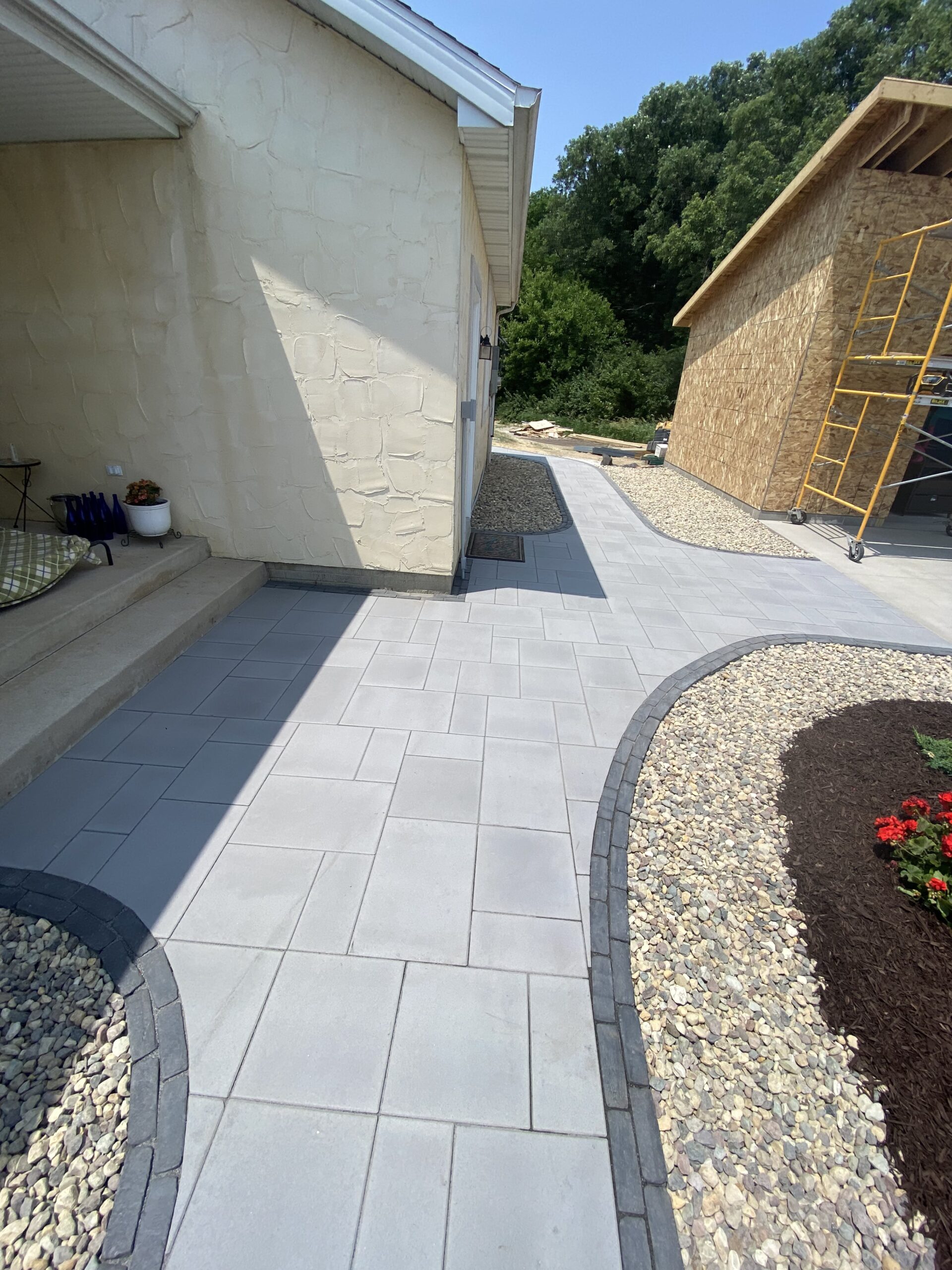 Krueger Lawn and Landscape's tranquil patio area with brick and stone pavers and pool backdrop