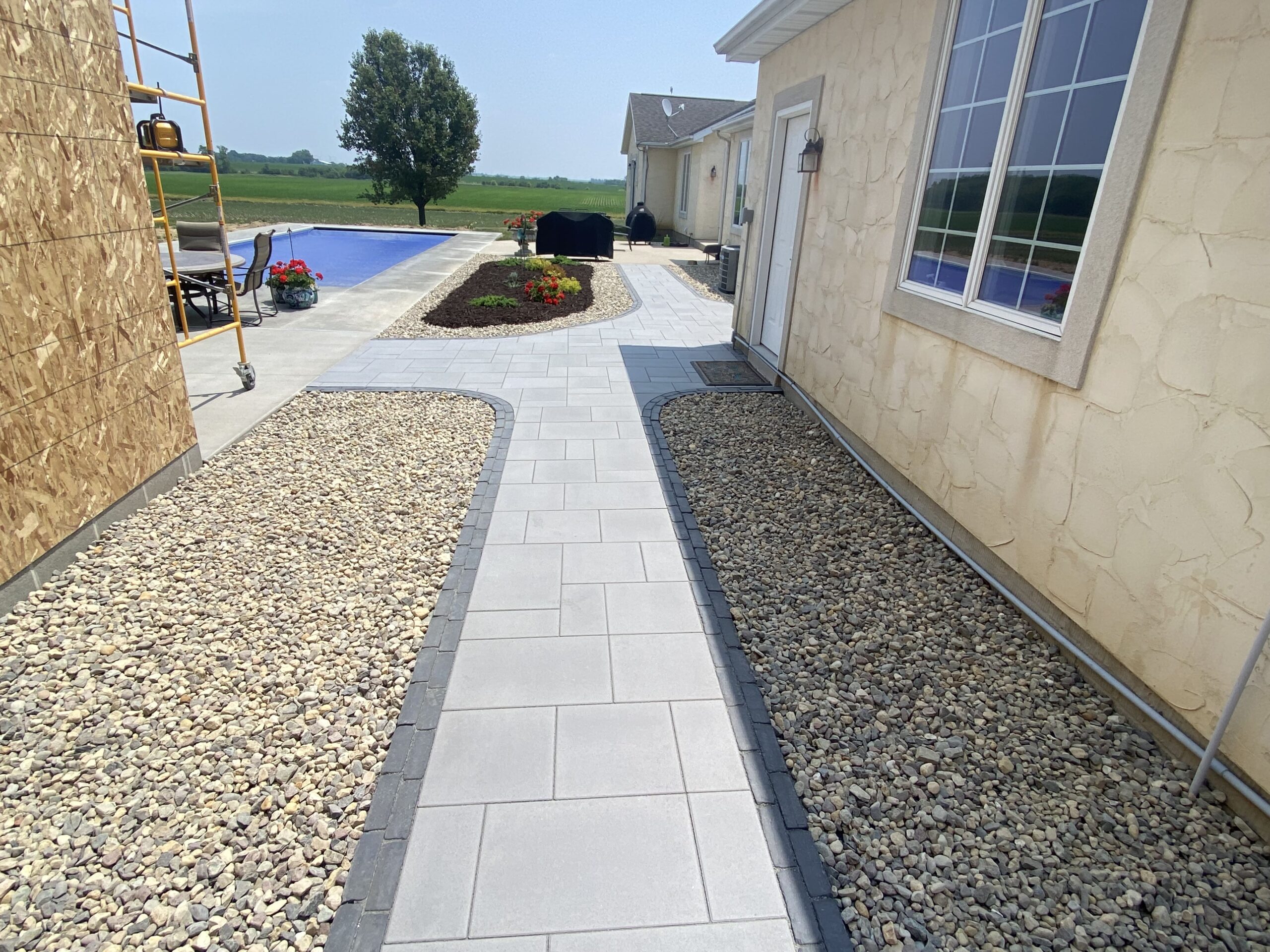 Krueger Lawn and Landscape's landscape design featuring brick and stone pavers by a pool.